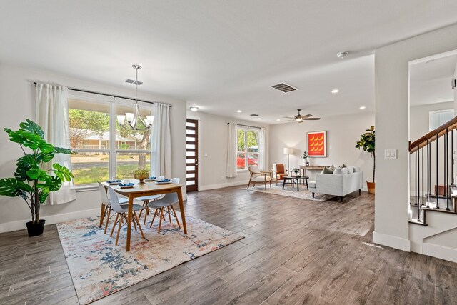 dining area with hardwood / wood-style floors and ceiling fan with notable chandelier