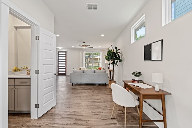 office space with light wood-type flooring, ceiling fan, and sink