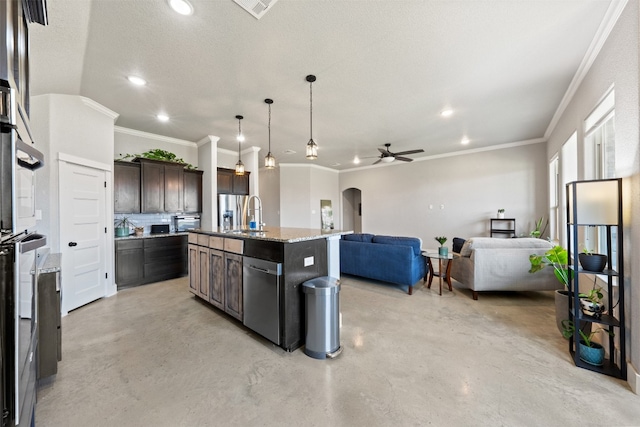 kitchen with dark brown cabinets, a center island with sink, stainless steel appliances, and ceiling fan