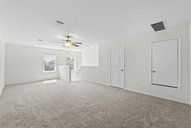 carpeted empty room featuring ceiling fan, visible vents, and baseboards