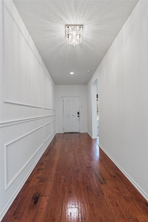 hallway with arched walkways, baseboards, and hardwood / wood-style floors