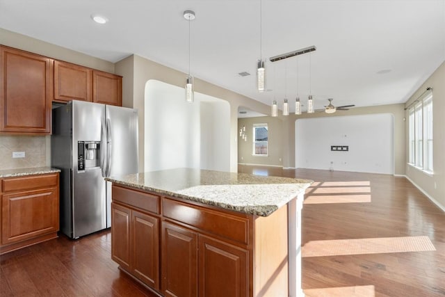 kitchen with arched walkways, decorative backsplash, open floor plan, dark wood-style flooring, and stainless steel refrigerator with ice dispenser