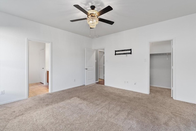 unfurnished bedroom with carpet floors, a closet, a spacious closet, ensuite bathroom, and ceiling fan