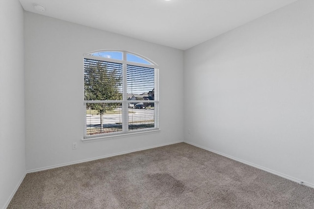 carpeted spare room featuring baseboards