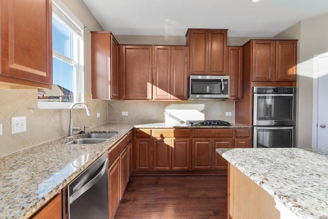 kitchen featuring a sink, appliances with stainless steel finishes, light stone countertops, dark wood-style floors, and tasteful backsplash