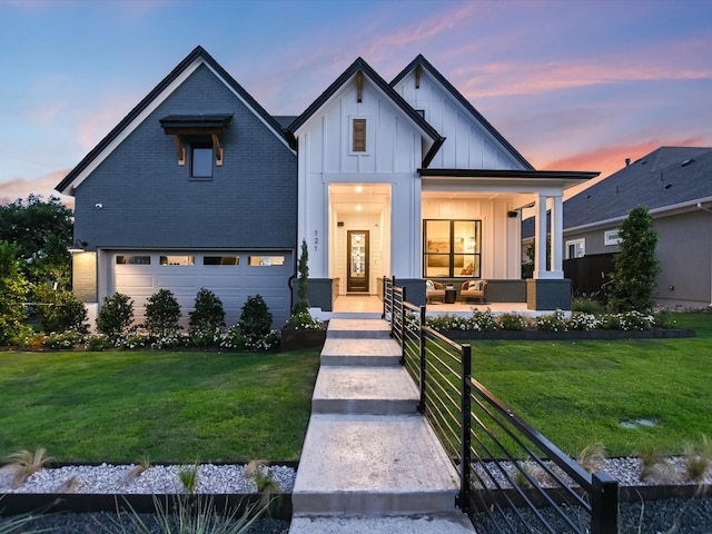 modern farmhouse style home featuring a porch, a lawn, and a garage