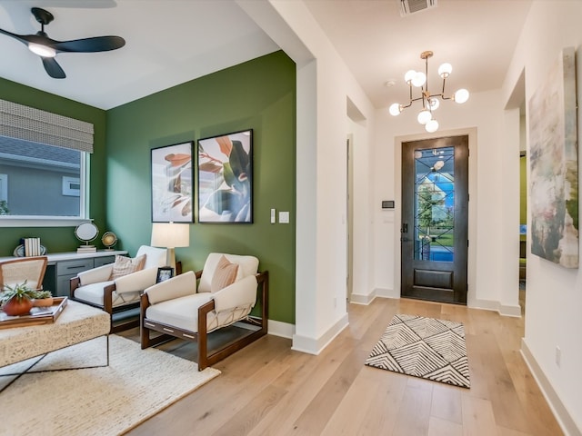 entrance foyer with ceiling fan with notable chandelier and light hardwood / wood-style floors