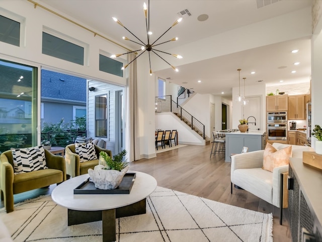 living room featuring an inviting chandelier, light wood-type flooring, and sink