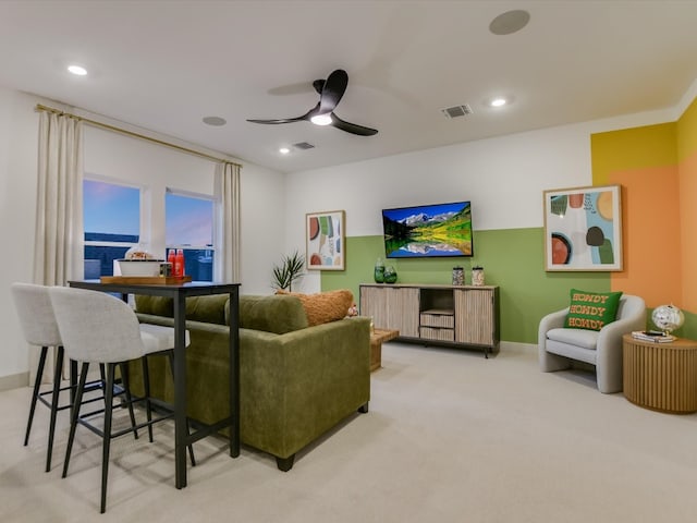 carpeted living room with a water view and ceiling fan