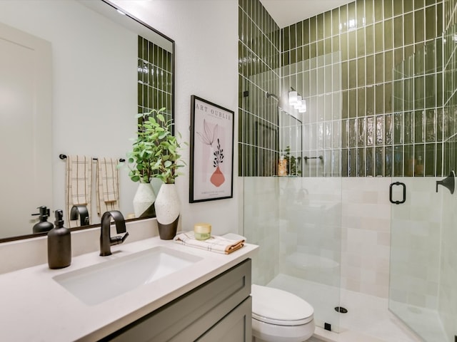 bathroom with a shower with shower door, vanity, and toilet