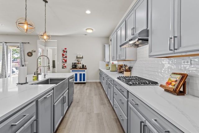 kitchen with appliances with stainless steel finishes, light hardwood / wood-style flooring, sink, gray cabinetry, and decorative light fixtures