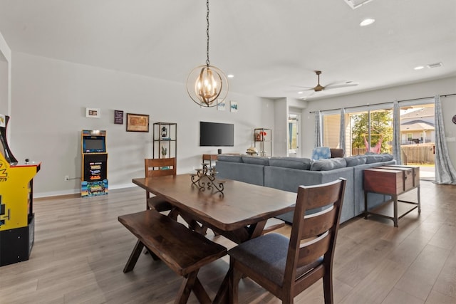 dining area featuring hardwood / wood-style flooring and ceiling fan with notable chandelier