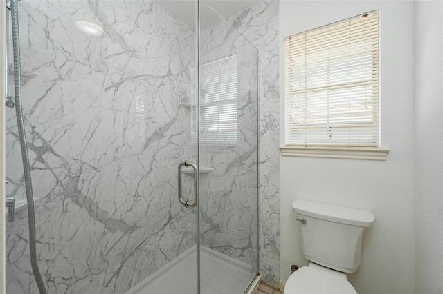 bathroom with a shower with shower door and toilet