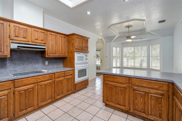 kitchen with decorative backsplash, cooktop, a textured ceiling, ceiling fan, and light tile patterned floors