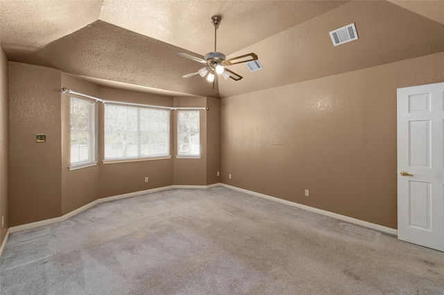 empty room with a textured ceiling, ceiling fan, light colored carpet, and vaulted ceiling