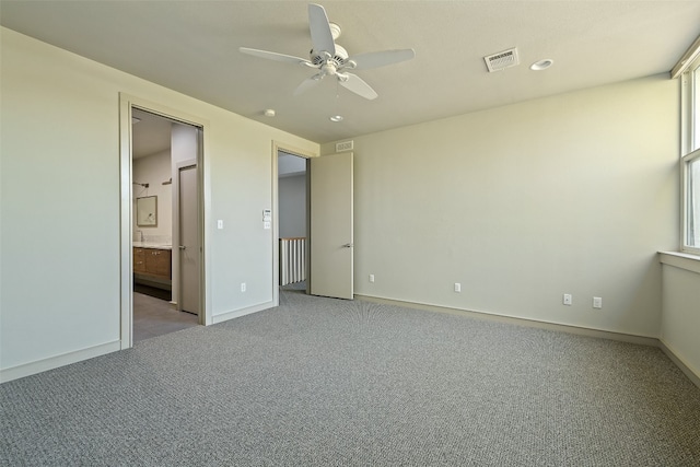 unfurnished bedroom featuring ceiling fan, ensuite bath, and light carpet