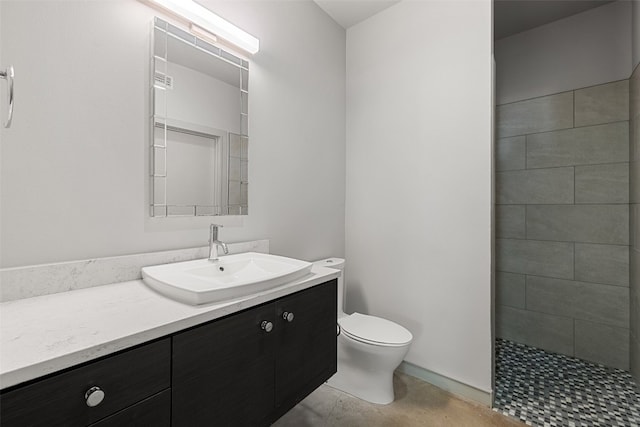 bathroom with a tile shower, vanity, and toilet