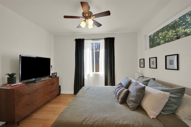 bedroom with ceiling fan, baseboards, and light wood-type flooring