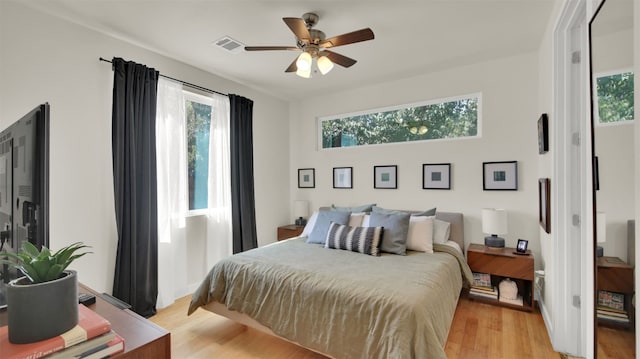 bedroom featuring light wood finished floors, visible vents, and ceiling fan