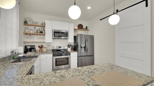 kitchen featuring white cabinets, stainless steel appliances, a sink, pendant lighting, and open shelves