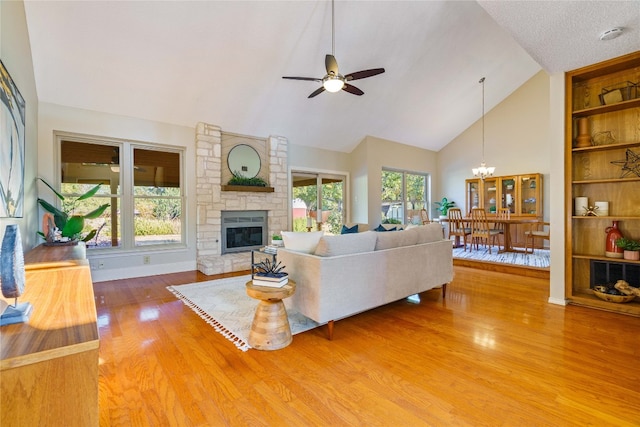 living room featuring a fireplace, plenty of natural light, hardwood / wood-style floors, and ceiling fan with notable chandelier