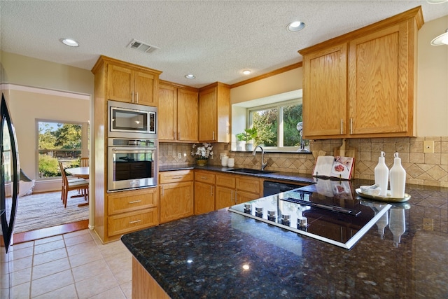 kitchen featuring backsplash, sink, light tile patterned floors, a textured ceiling, and stainless steel appliances