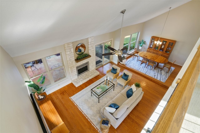 living room featuring ceiling fan with notable chandelier, hardwood / wood-style flooring, and lofted ceiling