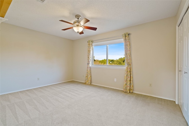 spare room with ceiling fan, light colored carpet, and a textured ceiling