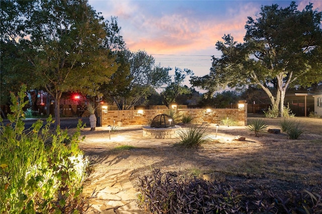 yard at dusk featuring a water view and a fire pit