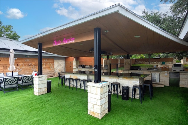 view of yard with ceiling fan, an outdoor bar, and exterior kitchen