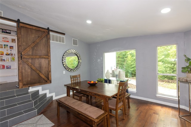 dining room with dark wood-type flooring, a barn door, and vaulted ceiling