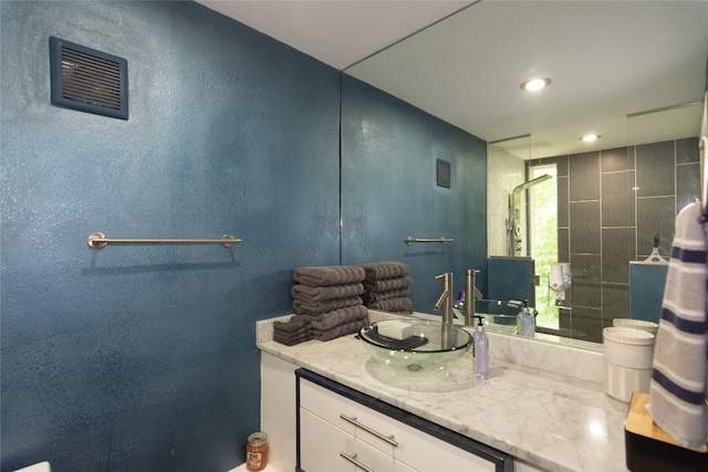 bathroom featuring a tile shower and vanity