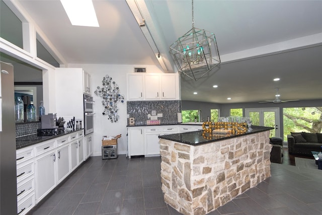 kitchen featuring dark stone countertops, ceiling fan, decorative backsplash, and white cabinets