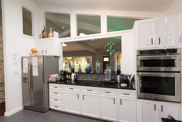 kitchen featuring white cabinets, stainless steel appliances, and dark tile patterned floors