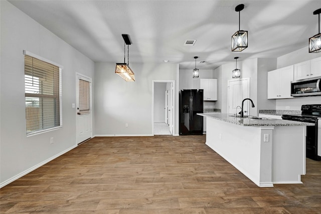 kitchen featuring wood-type flooring, white cabinets, a kitchen island with sink, and black appliances