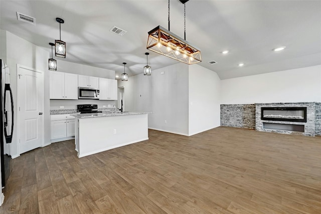 kitchen featuring wood-type flooring, hanging light fixtures, appliances with stainless steel finishes, an island with sink, and white cabinetry