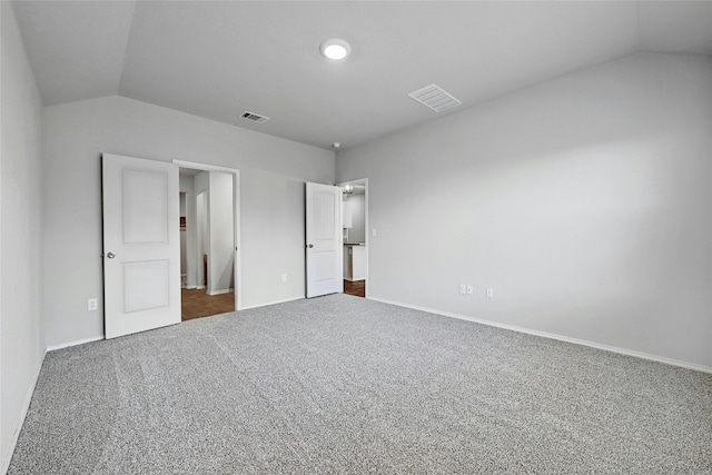 unfurnished bedroom with dark colored carpet and vaulted ceiling