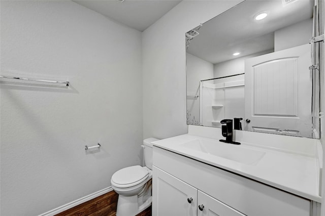 bathroom featuring hardwood / wood-style floors, toilet, vanity, and a shower