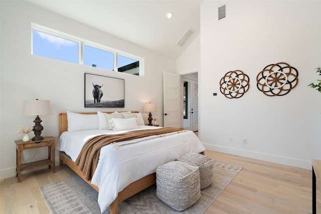 bedroom with high vaulted ceiling and light hardwood / wood-style flooring