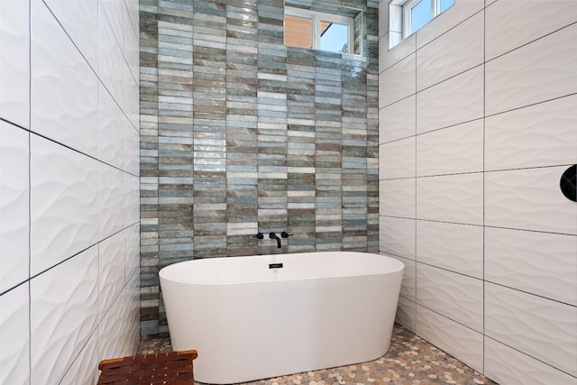 bathroom featuring a bath and tile walls