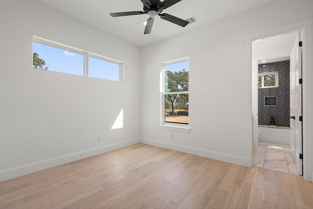 unfurnished bedroom with multiple windows, light hardwood / wood-style flooring, ceiling fan, and a fireplace