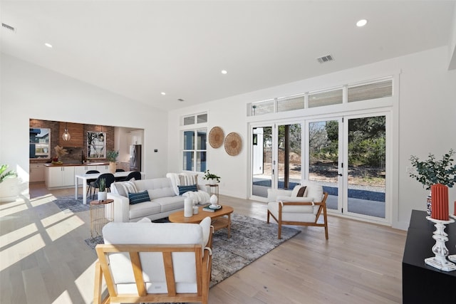 living room with vaulted ceiling, light wood-type flooring, and french doors