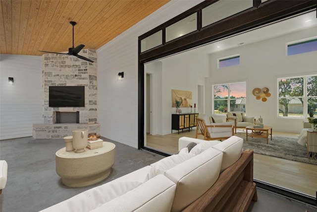 living room featuring ceiling fan, wooden ceiling, a towering ceiling, and concrete floors