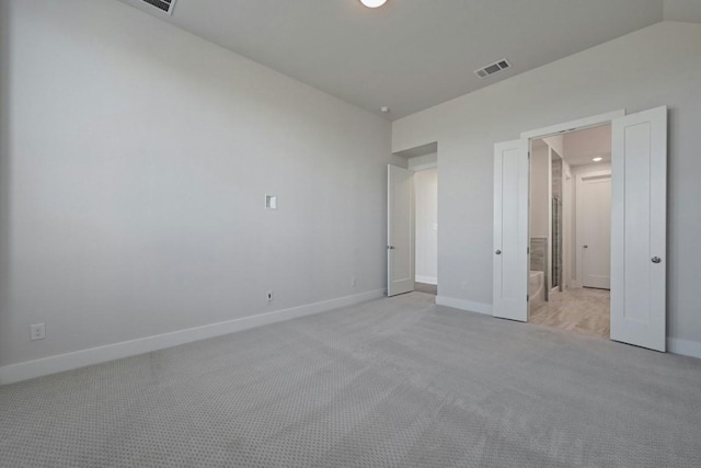 unfurnished bedroom featuring light colored carpet and vaulted ceiling