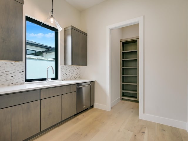 kitchen with hanging light fixtures, sink, stainless steel dishwasher, light hardwood / wood-style floors, and tasteful backsplash