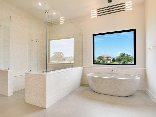 bathroom with tile patterned flooring, tile walls, and separate shower and tub