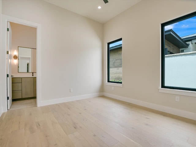 unfurnished bedroom with connected bathroom, light wood-type flooring, and ceiling fan