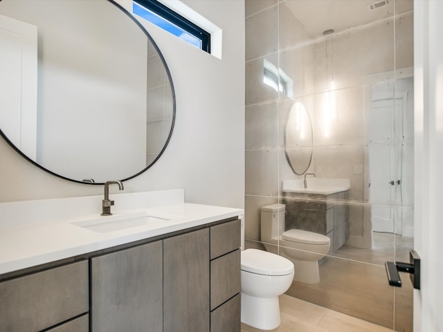 bathroom with vanity, toilet, tile walls, and a bidet