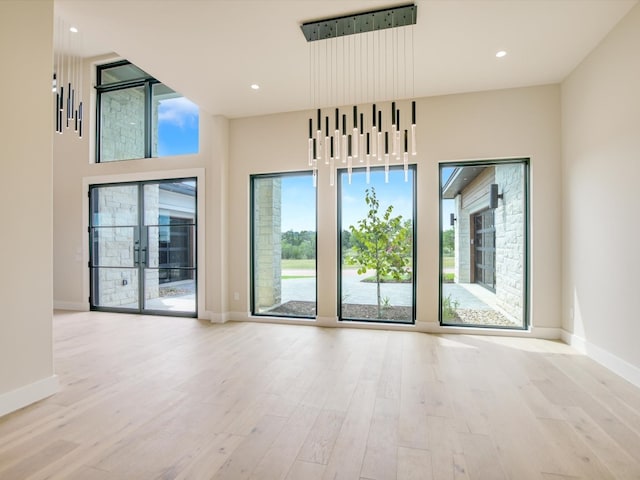 empty room featuring a towering ceiling and light hardwood / wood-style flooring