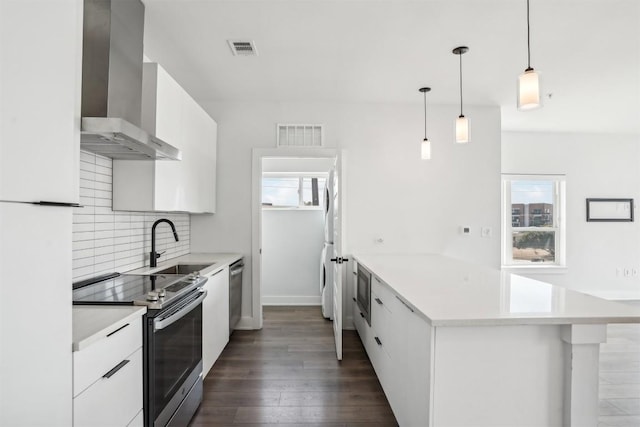 kitchen featuring white cabinetry, wall chimney exhaust hood, pendant lighting, decorative backsplash, and appliances with stainless steel finishes